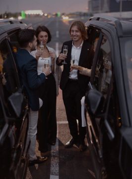 Group of friends drinking between 2 limousines